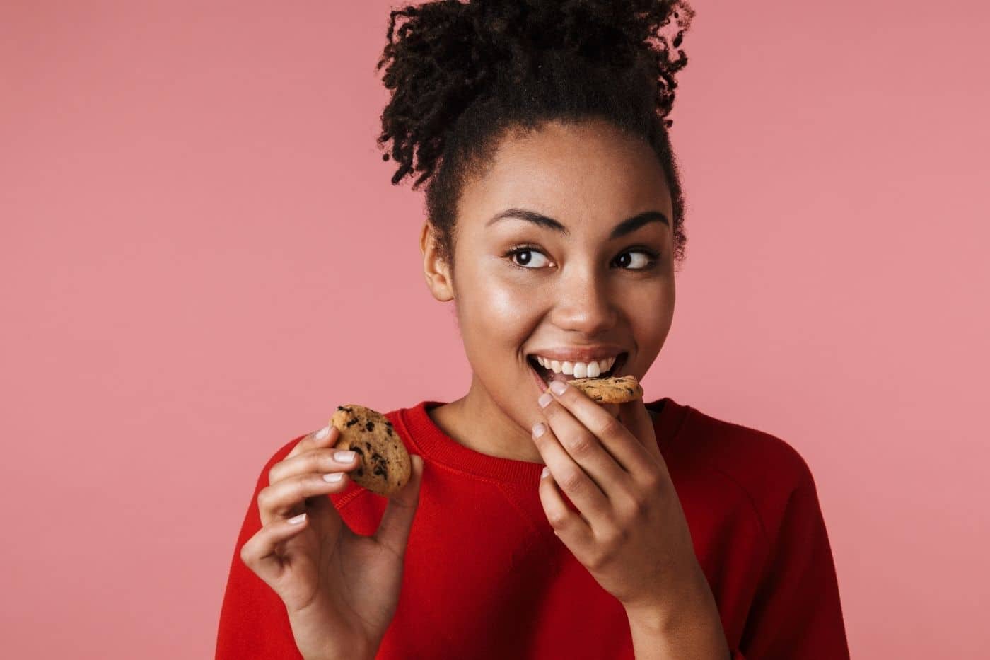 Woman nibbling on a chocolate chip cookie.