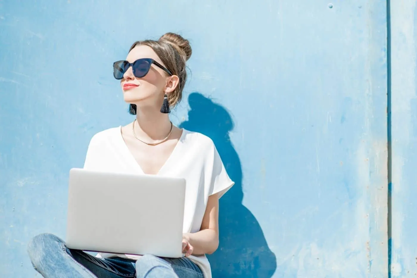 Peer Sales Agency holding laptop, face toward the sun and smiling.