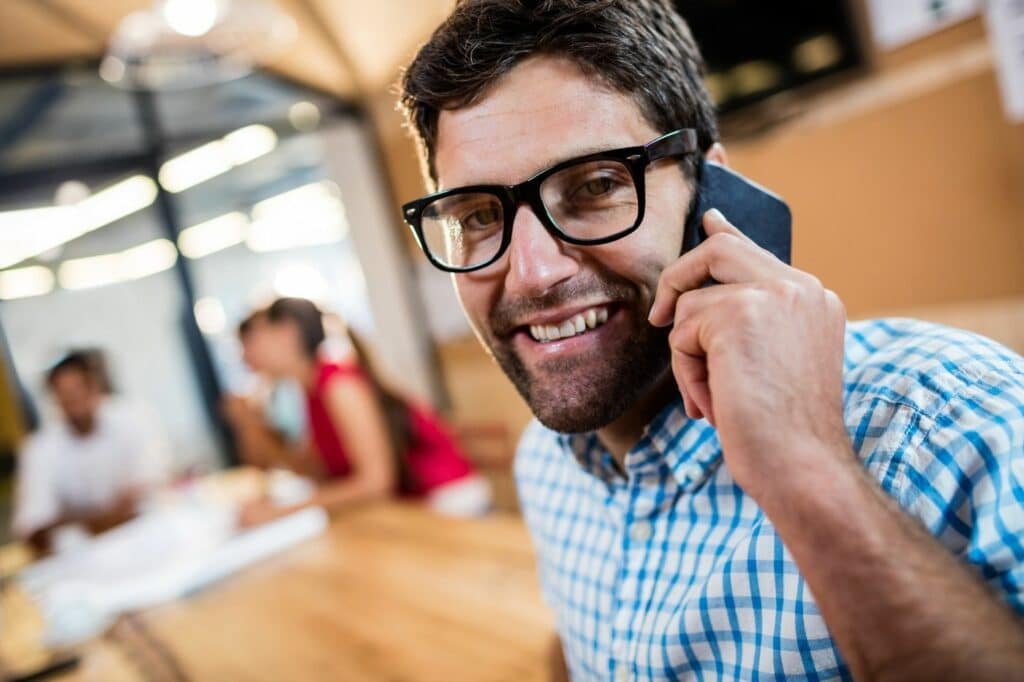 Man at Peer Sales Agency smiling with a phone to his ear.