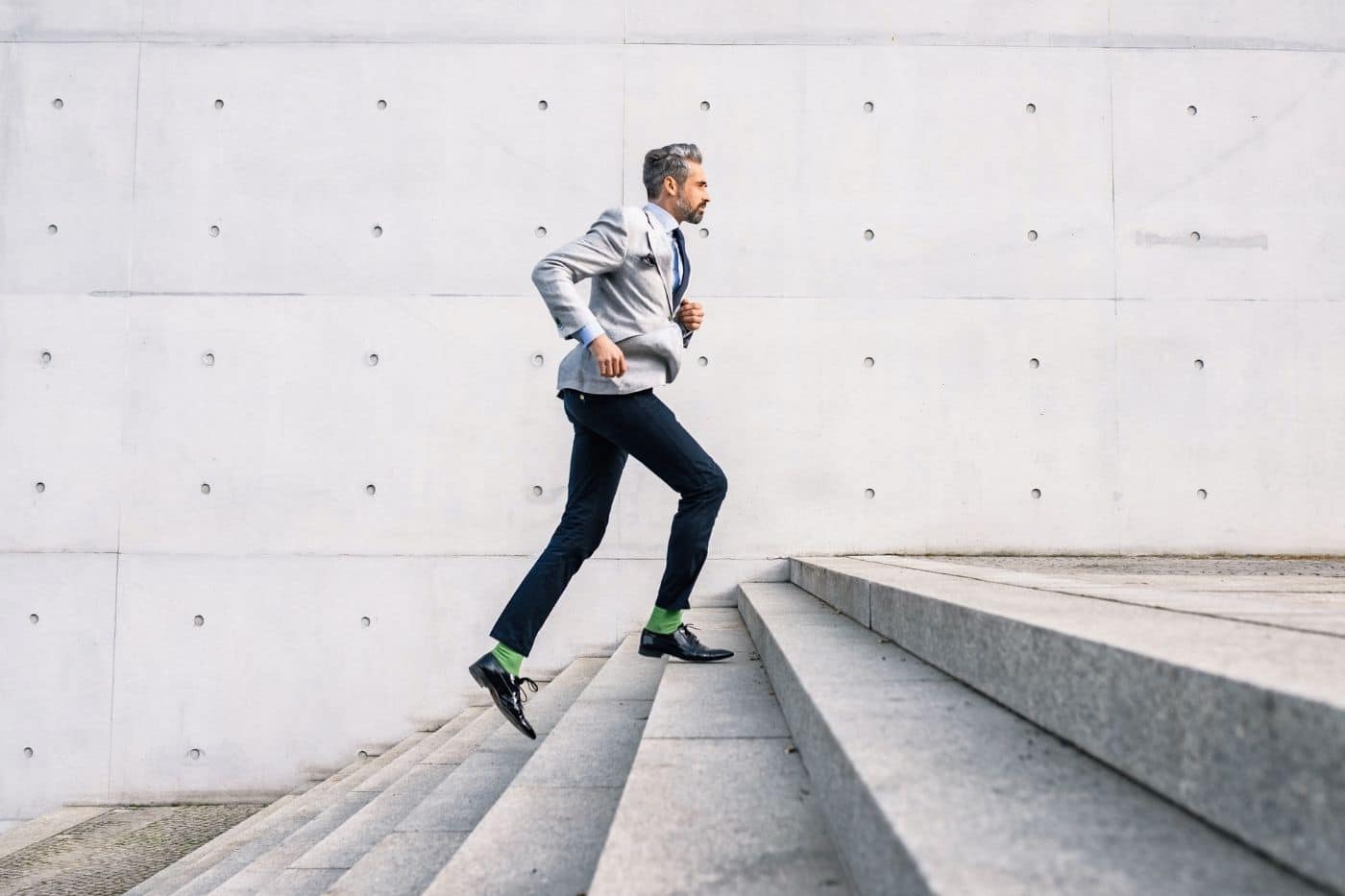 Man in suit with green socks running up stairs.
