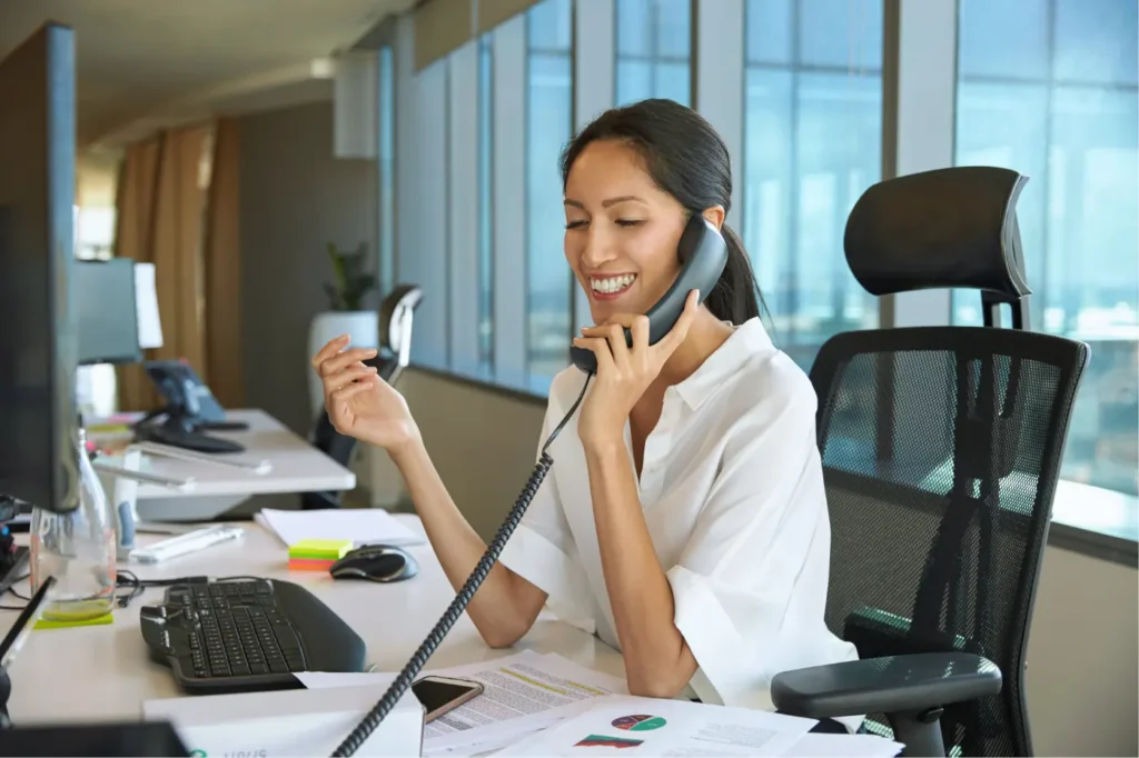 A female sales representative talks on the phone with a lead generated by her B2B outbound sales strategy.