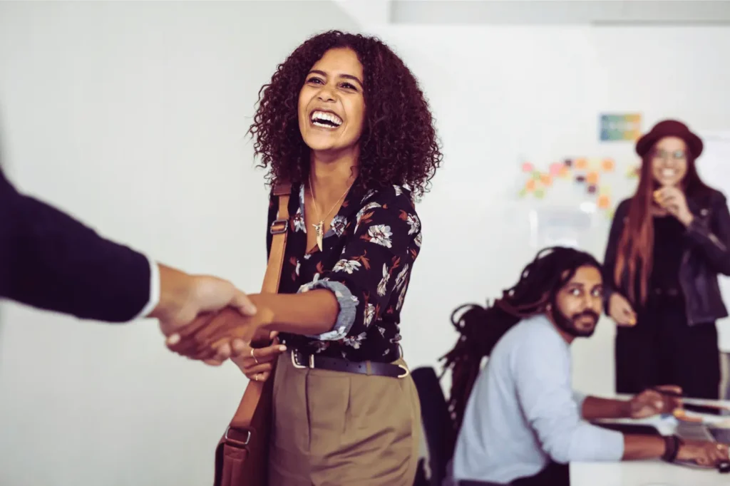 A woman and her coworkers greeting an unseen sales representative for an outbound sales meeting.