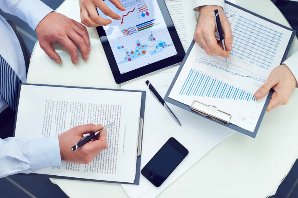 Business professionals reviewing charts, reports, and digital analytics during a collaborative meeting, illustrating a modern sales framework for B2B sales enablement and data-driven decision making.