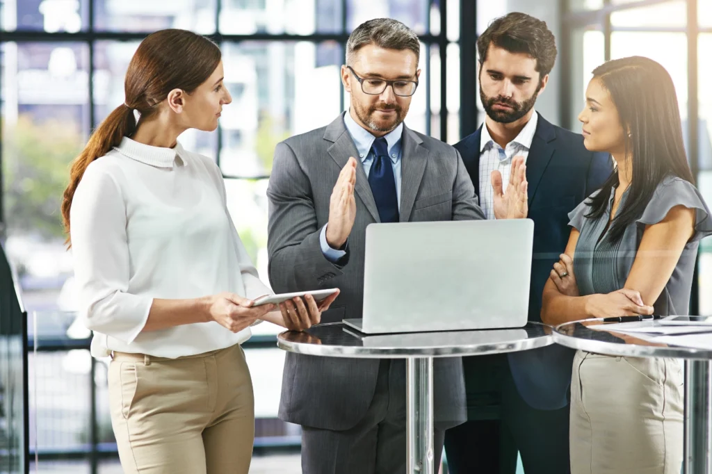 Sales and marketing alignment among business professionals collaborating around a laptop